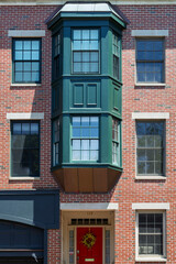Obraz premium Red brick building facade with green bay window in Charlestown Boston 
