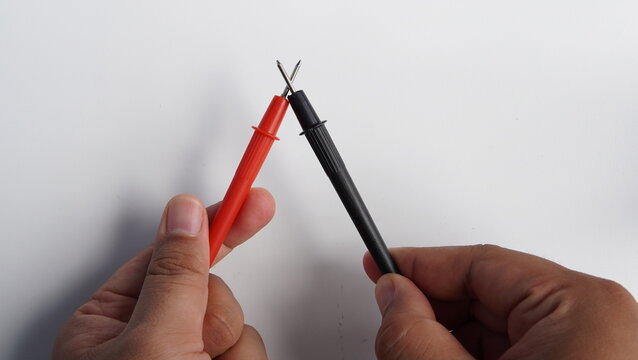 hands touching multimeter probes for testing. technician holding electronic multimeter testing tools