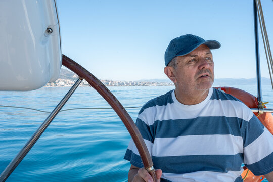 Mature man steering sailboat on a calm blue sea