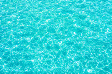 Fototapeta premium Turquoise tropical water surface with sunlight ripples, crystal clear ocean pool background, bright blue sea water texture for summer travel