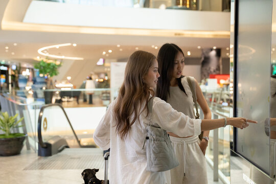 Women using interactive digital screen for navigation in shopping mall