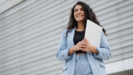 Fototapeta premium Smiling confident woman in blue suit holding documents outdoors
