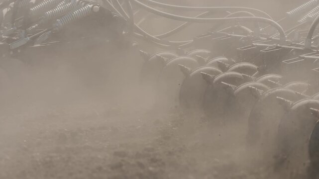 Close up of agricultural disc harrow cultivating dry soil in farmland. Modern tillage equipment preparing field for planting during farming season.