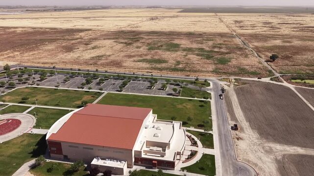 Stunning aerial perspective revealing Lemoore College in California, highlighting its modern architecture, empty parking lot, and the vast, arid landscape surrounding the campus