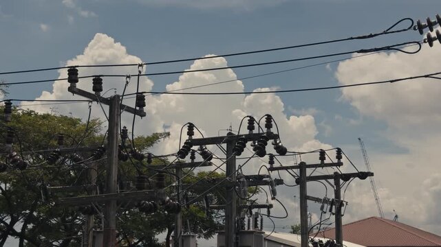 Close up view of electricity pole tops featuring transmission and distribution lines, silicone rubber insulators and power wires against the sky in an energy infrastructure scene.