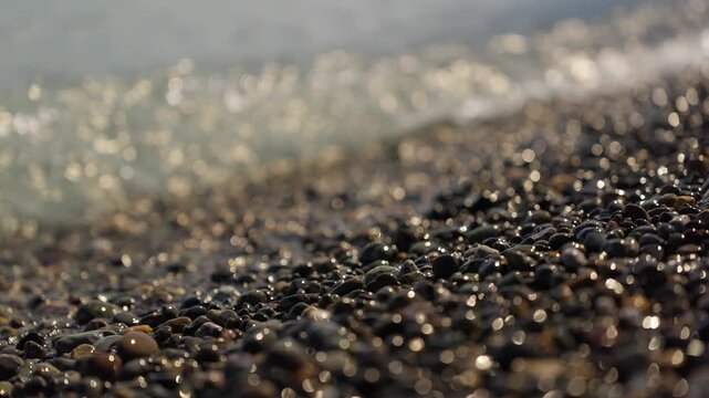 Glacial water laps against a pebble shoreline near El Chalt&eacute;n, Santa Cruz, Argentina, with sparkling reflections and shallow depth of field highlighting rounded stones, close-up shot.