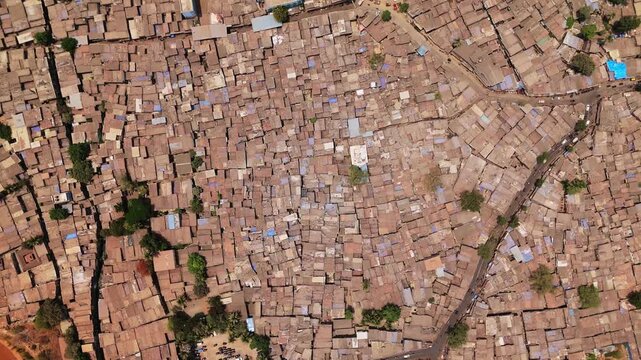 High altitude top down perspective showing the densely packed rooftops and narrow streets of the dharavi slum, one of the world's largest informal settlements located in mumbai, india