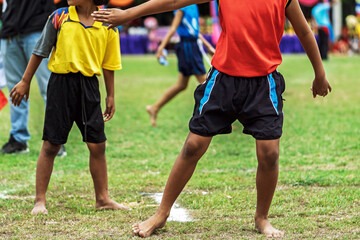 Schoolgirls running barefoot relay race at sports day. Young schoolgirls competing in relay race on grass field, Running barefoot and holding colorful batons during an outdoor school sports festival.