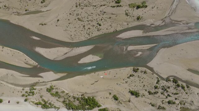 Kitesurfers navigate braided channels of R&iacute;o de las Vueltas near El Chalt&eacute;n, Santa Cruz, Argentina, crossing glacial meltwater and exposed alluvial bars, top down drone tracking shot.