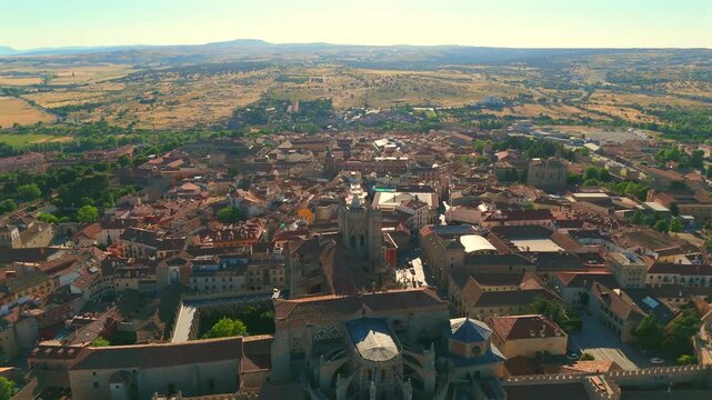 Aerial drone approaches a historic stone church flying low over terracotta rooftops in Avila Spain