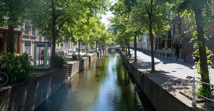 Historic canal houses and arched bridge in Delft City Centre on sunny spring day, Netherlands