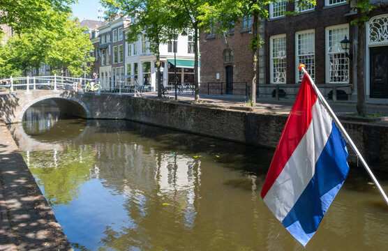 Dutch flag on canal boat beside historic Delft City Centre waterfront in spring sunlight