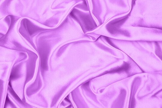 Elegant purple satin silk fabric texture background with soft ripples and folds.