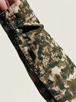 Military camouflage uniform sleeve in a formal salute showing detailed fabric texture and seams for national honor and veteran ceremonies