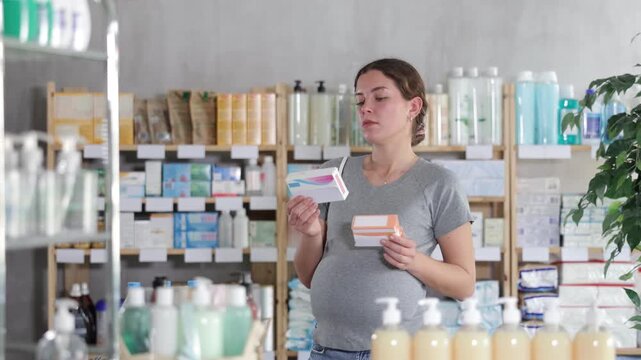 Pregnant woman buys toxicosis pills at a pharmacy. Woman chooses cold pills that can be used by pregnant women. High quality 4k footage