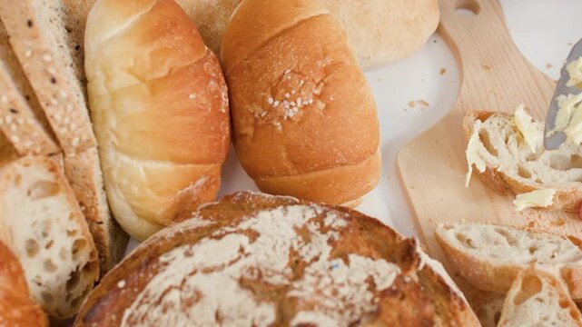 Spreading Butter on Sliced Baguette with Assorted Bakery Breads