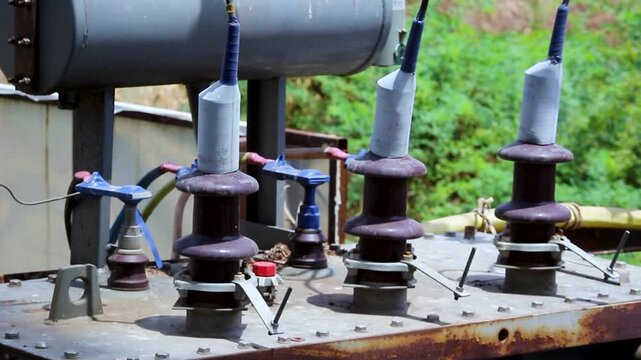 Close-up of transformer bushings and high voltage insulators at an electrical distribution site. Ideal for power grid, electricity infrastructure, utility, and energy industry projects.