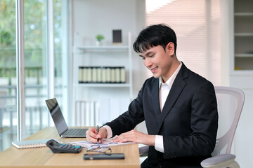 Obraz premium Asian businessman reviewing financial documents at office desk