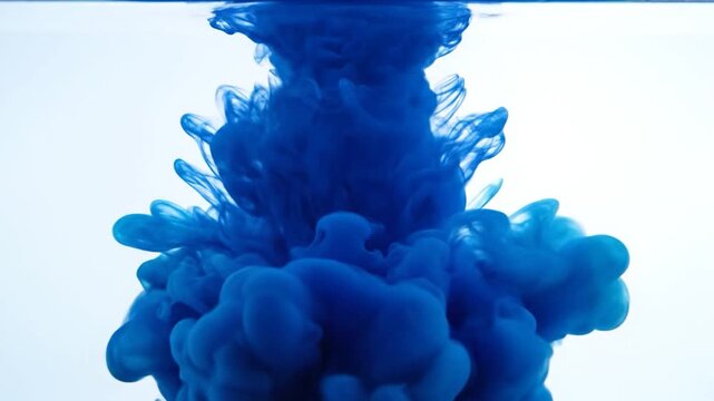 Blue ink cloud swirls in clear water against white background