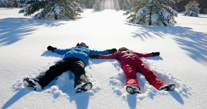 Two people making snow angels together.