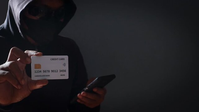 Anonymous cybercriminal using a smartphone and credit card in a dark environment, representing online fraud, phishing attacks, identity theft, financial scams, and cybersecurity threats.