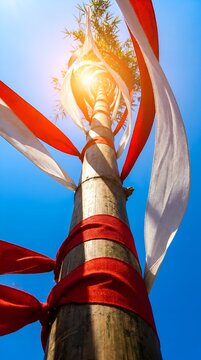 Vertical Bamboo Pole Decorated with Red and White Ribbons Against Blue Sky