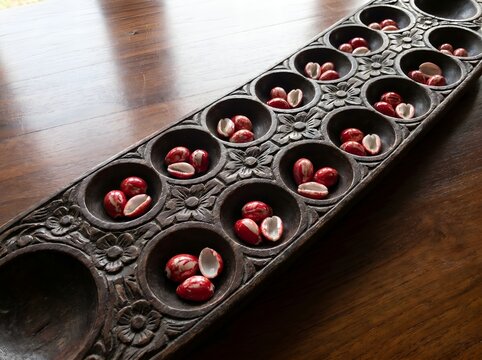 African Mancala Game Board with Seeds on Table