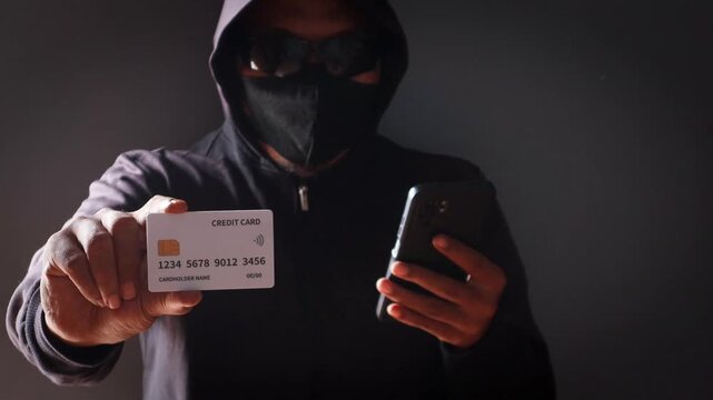 Anonymous cybercriminal using a smartphone and credit card in a dark environment, representing online fraud, phishing attacks, identity theft, financial scams, and cybersecurity threats.