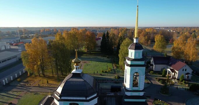 Aerial flyby shot of a classic Russian Orthodox church bathed in golden morning light with long shadows cast across a frosty lawn