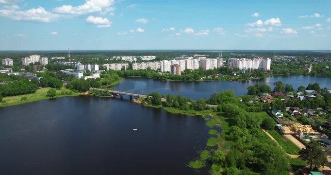 Aerial forward flying shot over a picturesque town situated on the banks of a wide river with a road bridge on a sunny summer day