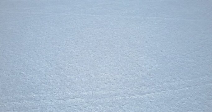 Top-down aerial view of a vast flat snow field displaying subtle wind patterns and faint surface textures