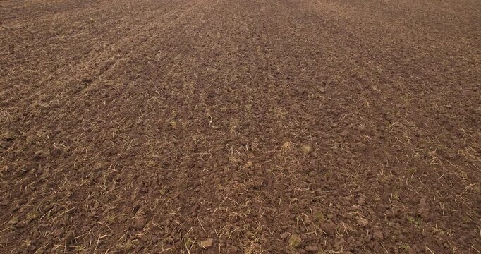 Low altitude aerial forward flying shot directly over the rough texture of freshly plowed dark brown agricultural soil