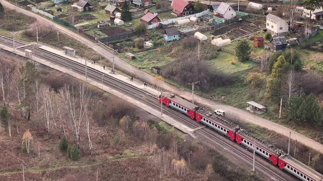 Commuter train arriving at a platform near a dacha settlement during autumn, trips to the countryside, suburban life and public transport