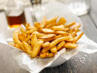 Naklejka premium Close up of crispy golden french fries in a bowl lined with paper on