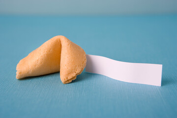 Naklejka premium Close up of a single fortune cookie with a blank white paper slip on