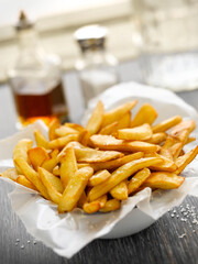 Naklejka premium Close up of crispy golden french fries in a bowl lined with paper on