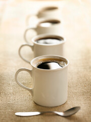 Naklejka premium High angle view of four white coffee mugs lined up in a row on a