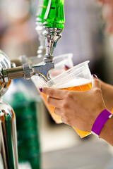 Naklejka premium Close up of a bartender pouring draft beer from a tap into a plastic