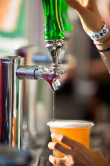 Naklejka premium Close up of a bartender pouring draft beer from a tap into a plastic