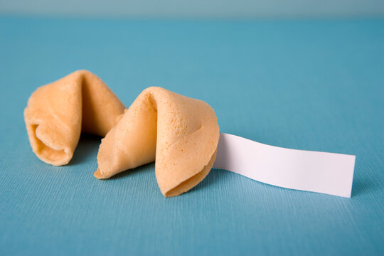 Two golden fortune cookies on a blue textured background with a blank