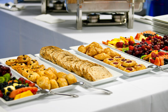 Catering buffet table filled with fresh pastries, bread, and fruit