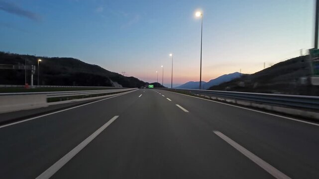 POV driving on modern highway with bright lights illuminating the road at night. Transportation, travel and infrastructure concept, 4k