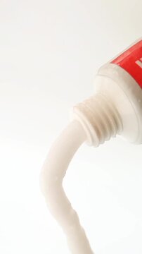 White cream coming out of a tube on white background, medical, cosmetic or skincare product. vertical clip