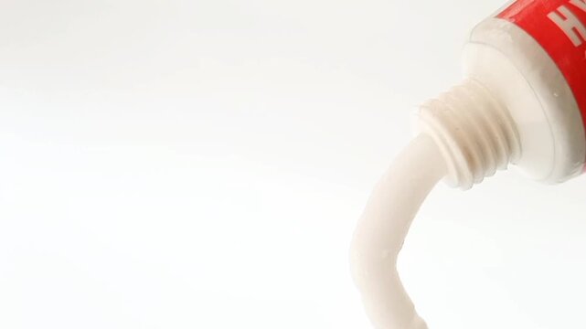 White cream coming out of a tube on white background, medical, cosmetic or skincare product