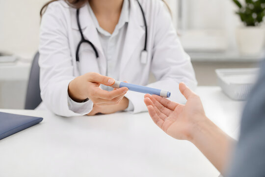 Clinician handing injection pen to patient in consultation