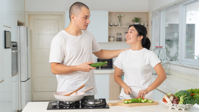 Happy Young Couple Cooking and Chopping Fresh Vegetables Together in Bright Kitchen
