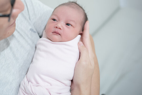 High Angle View of Father Holding and Looking at Swaddled Newborn Baby Girl
