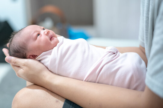 Side View of Father Carefully Cradling Swaddled Newborn Baby Girl in His Arms