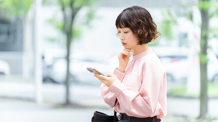 スマートフォンを使いながら考えるビジネスウーマン, Businesswoman Thinking While Using a Smartphone © Trickster*
