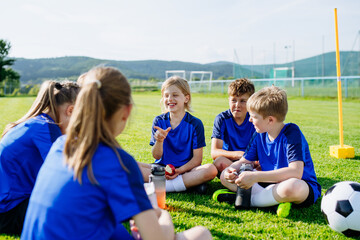 Naklejka premium Children relaxing together after youth football training and exercise.